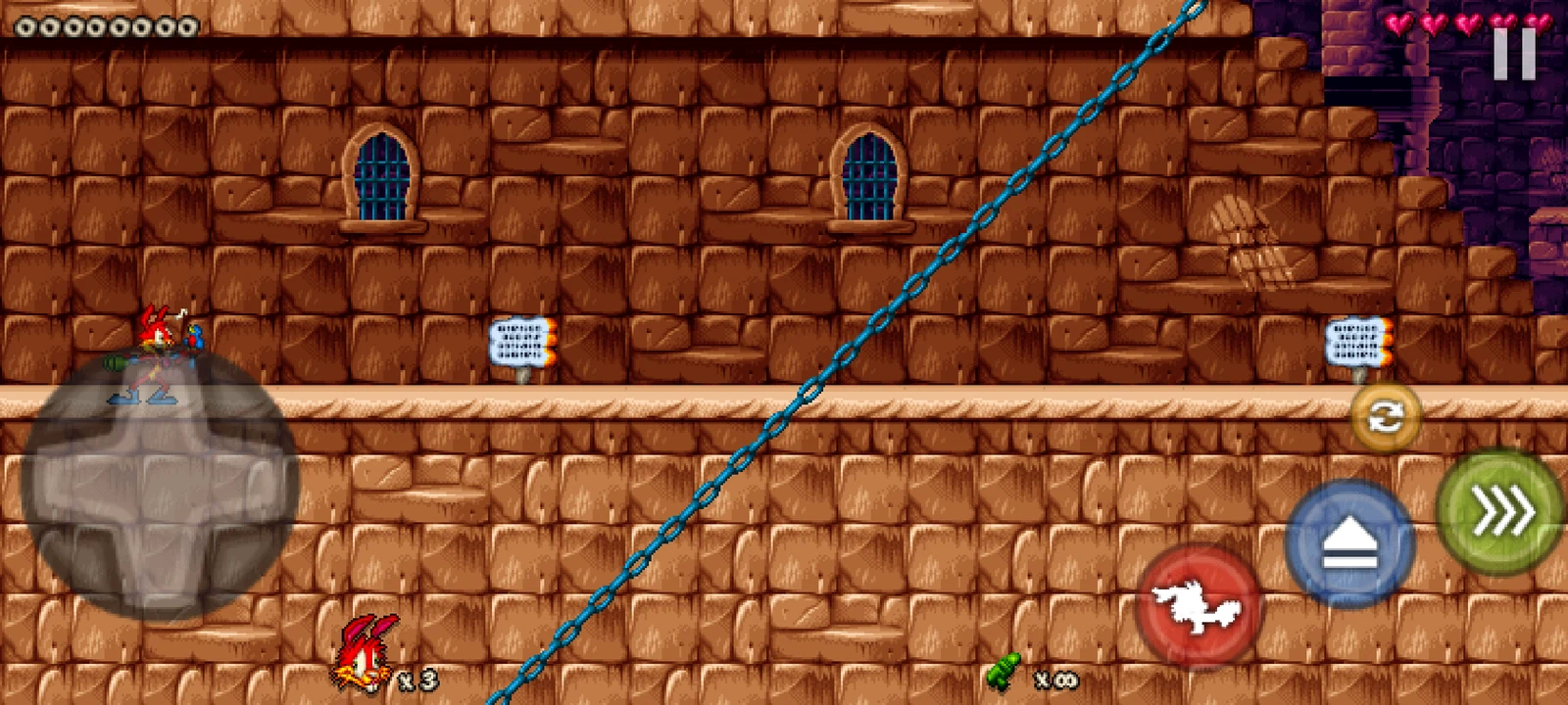 První level Jazz Jackrabbit 2 na telefonu, vlevo dole je směrový kříž a vpravo kulatá tlačítka na střelbu a skok
